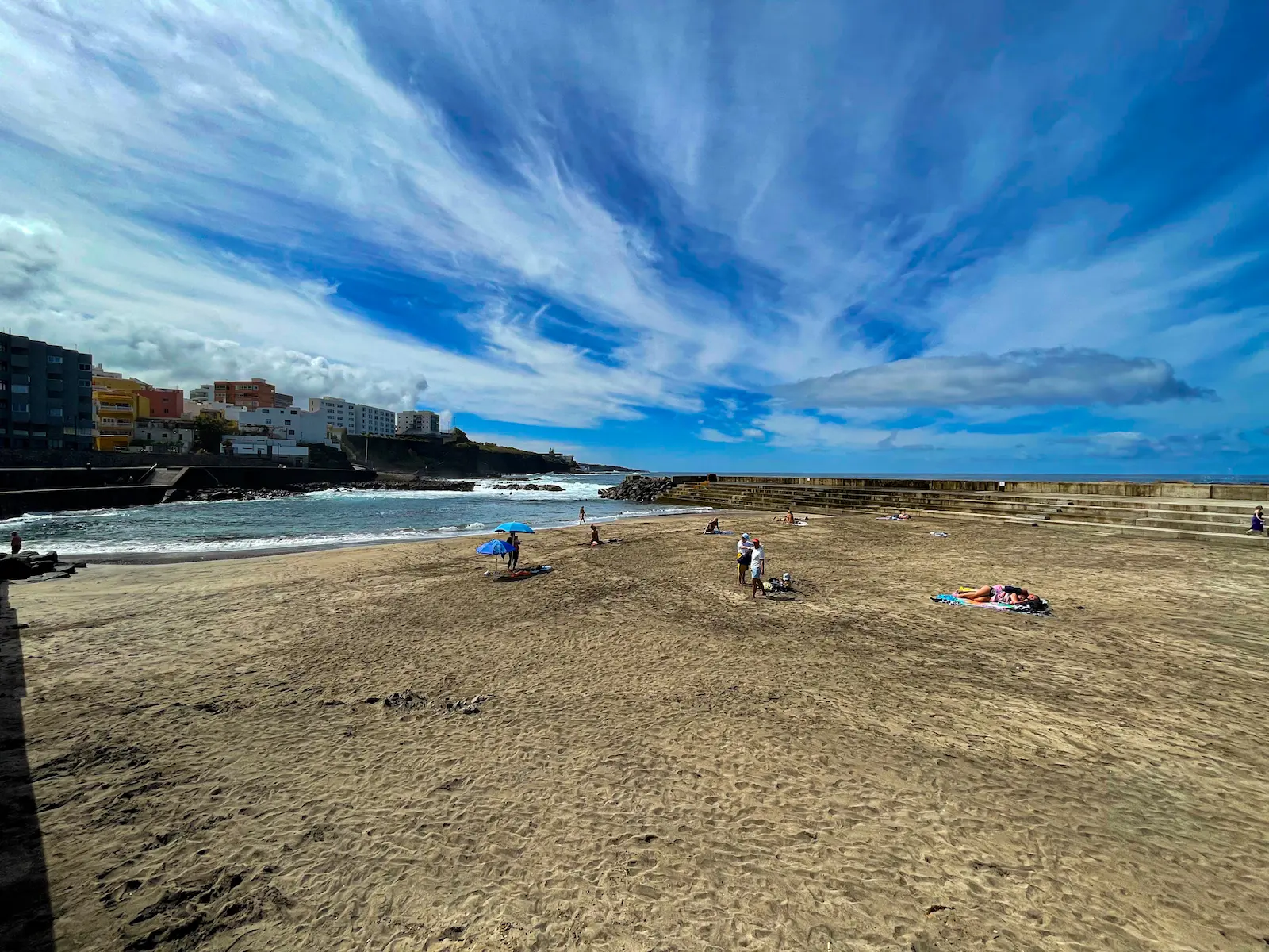 Bajamar Beach Tenerife with black sand and ocean waves under a dramatic blue sky