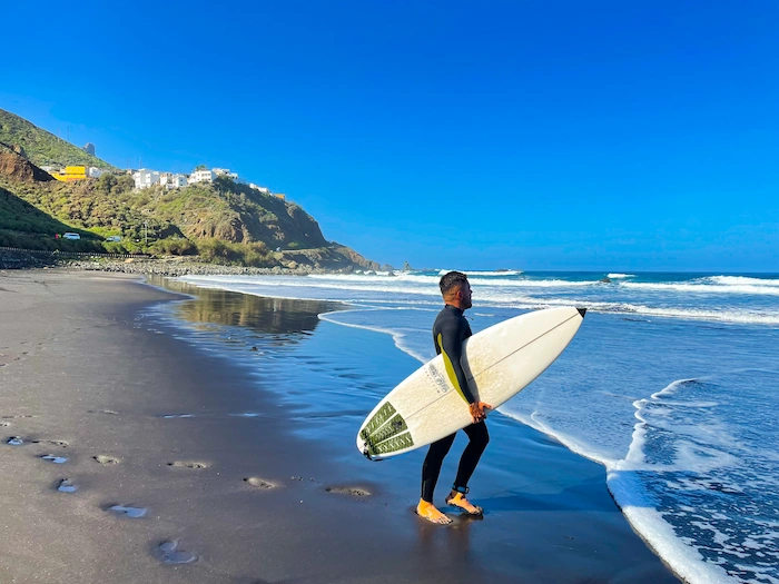 Surfer with board on Playa de Benijo’s black sand