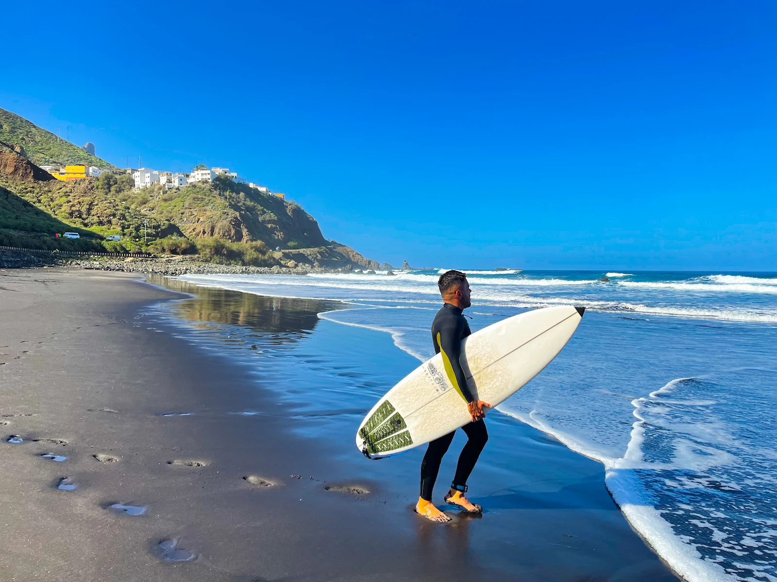 Surfer with board on Playa de Benijo’s black sand