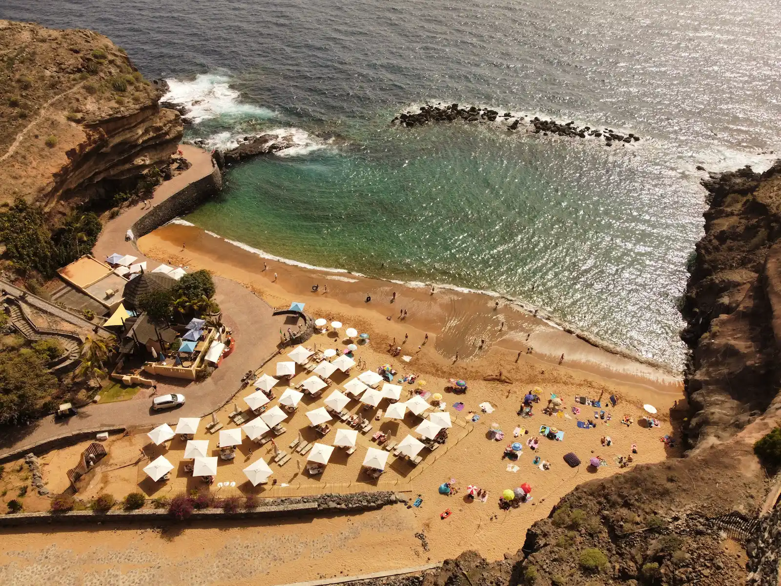 Aerial view of Playa Abama with golden sand and white parasols beside turquoise water