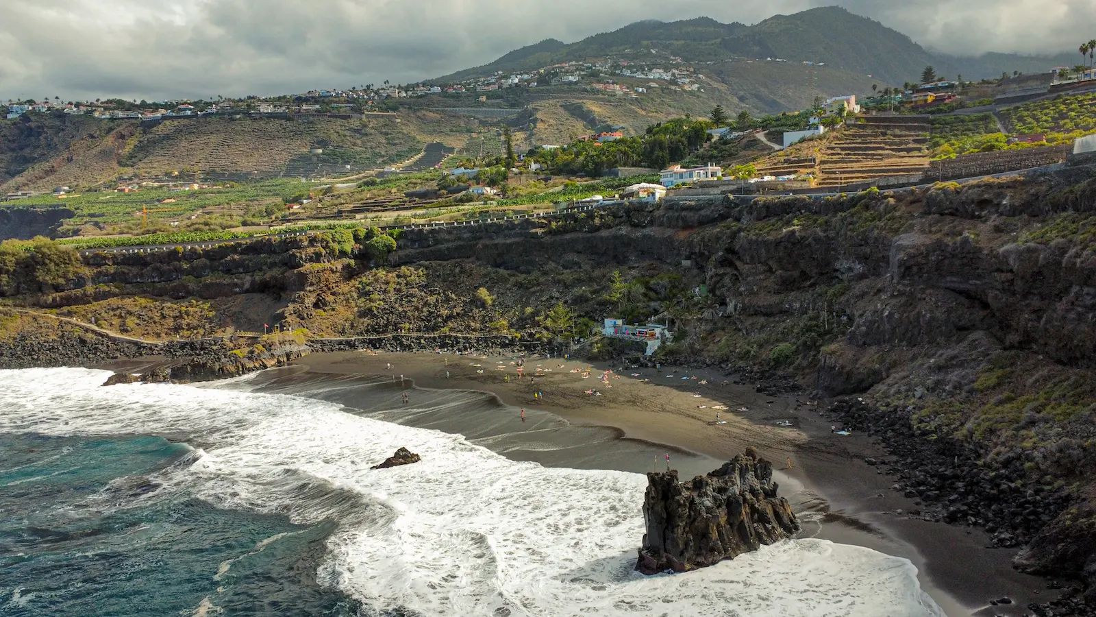 El Bollullo Beach seen from above with waves crashing on black sand