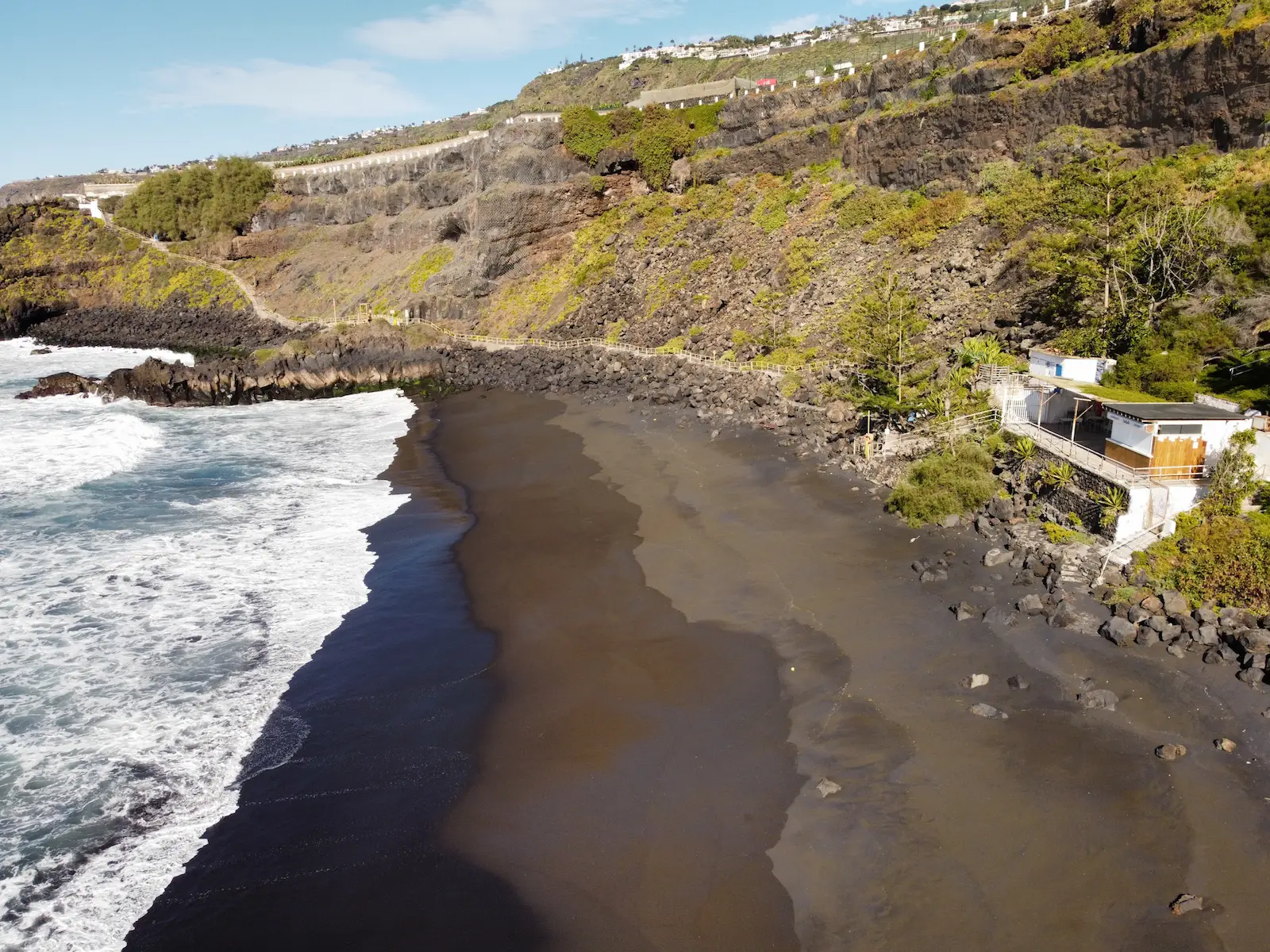 Aerial view of El Bollullo Beach with black volcanic sand and dramatic cliffs