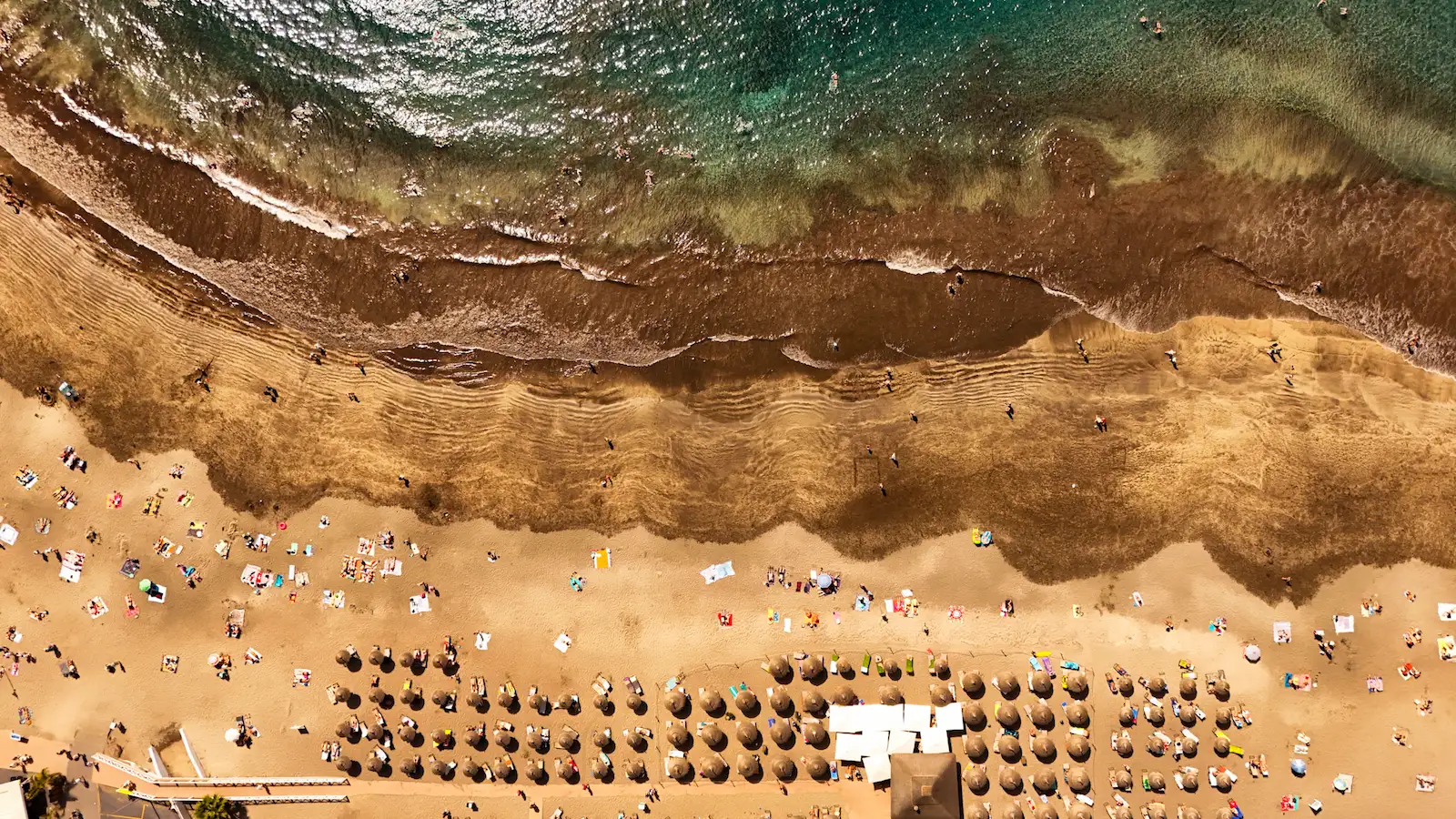Aerial view of Playa Fañabé with umbrellas and golden shoreline