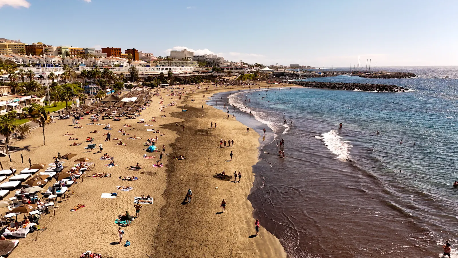 Wide view of Playa Fañabé beach in Tenerife with families enjoying the sun and shallow waves