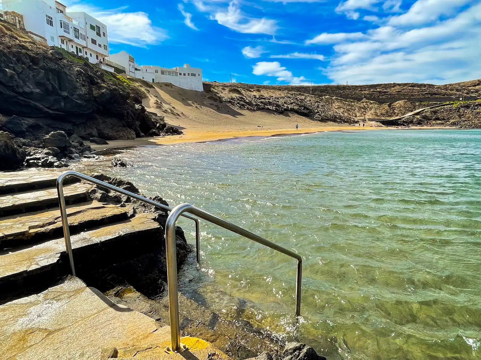 Stone steps into clear beach water at Playa Grande Tenerife