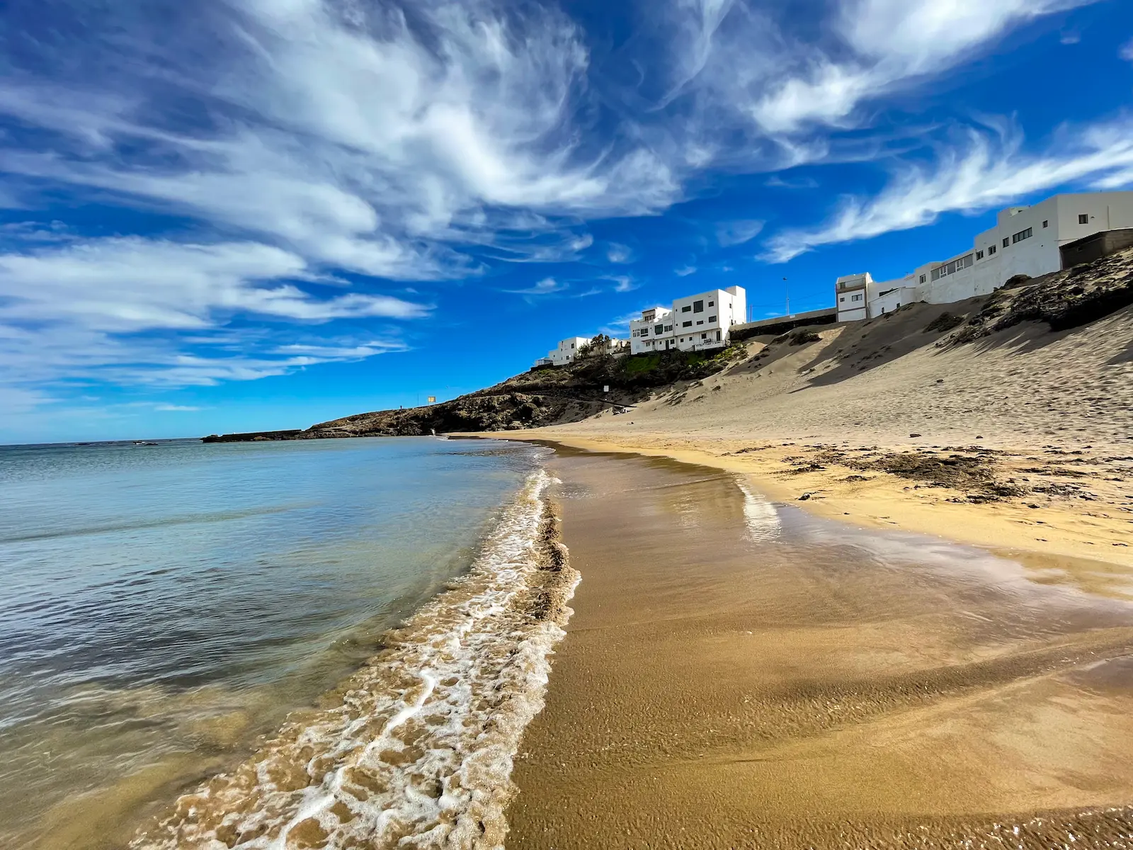 Playa Grande shoreline with golden sand, blue sky and gentle waves in Tenerife