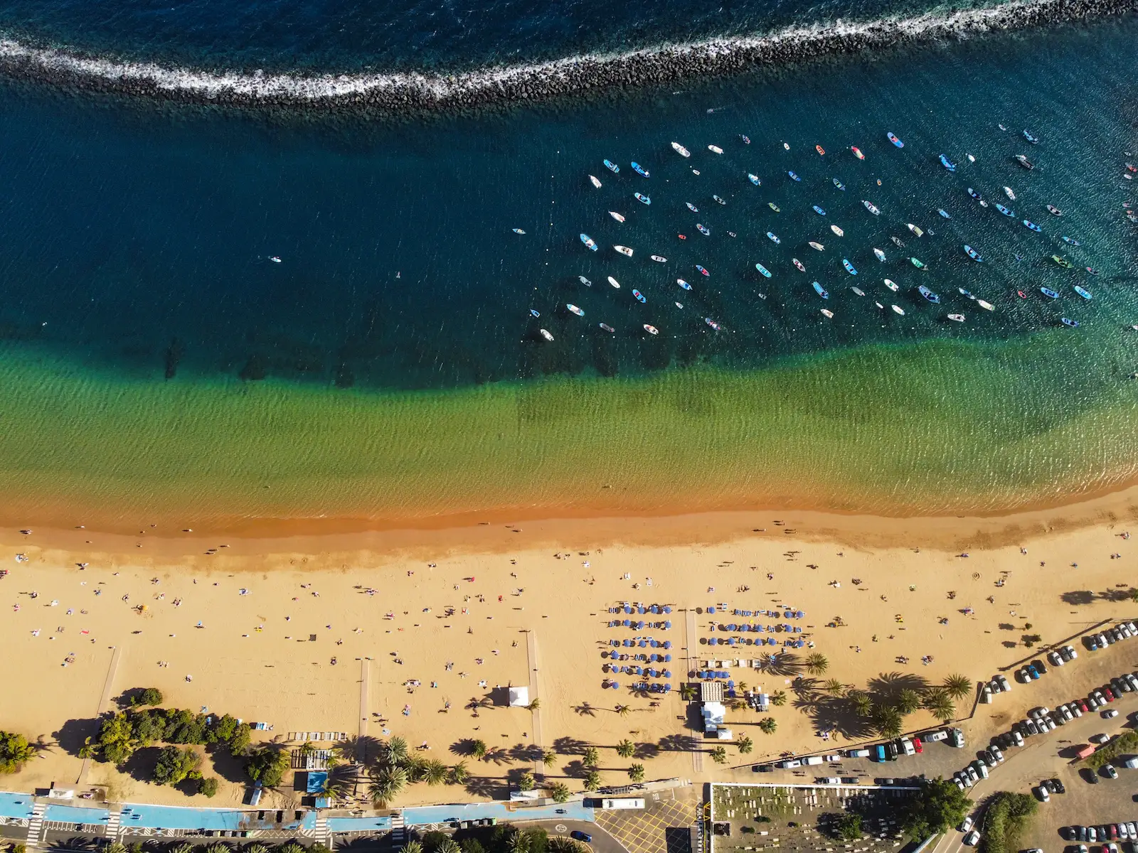 Top-down aerial view of Playa de Las Teresitas with breakwater and boats in the ocean