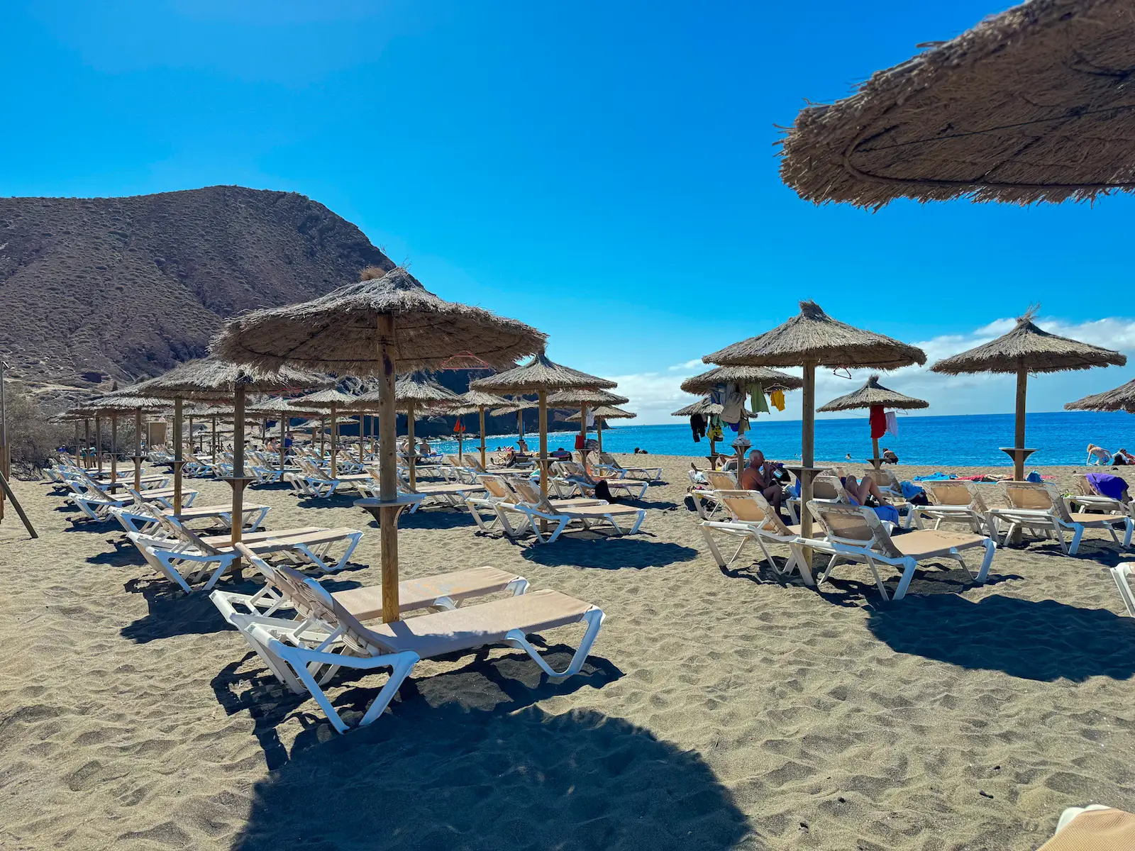 Sunbeds and parasols on La Tejita beach with Montaña Roja in the background