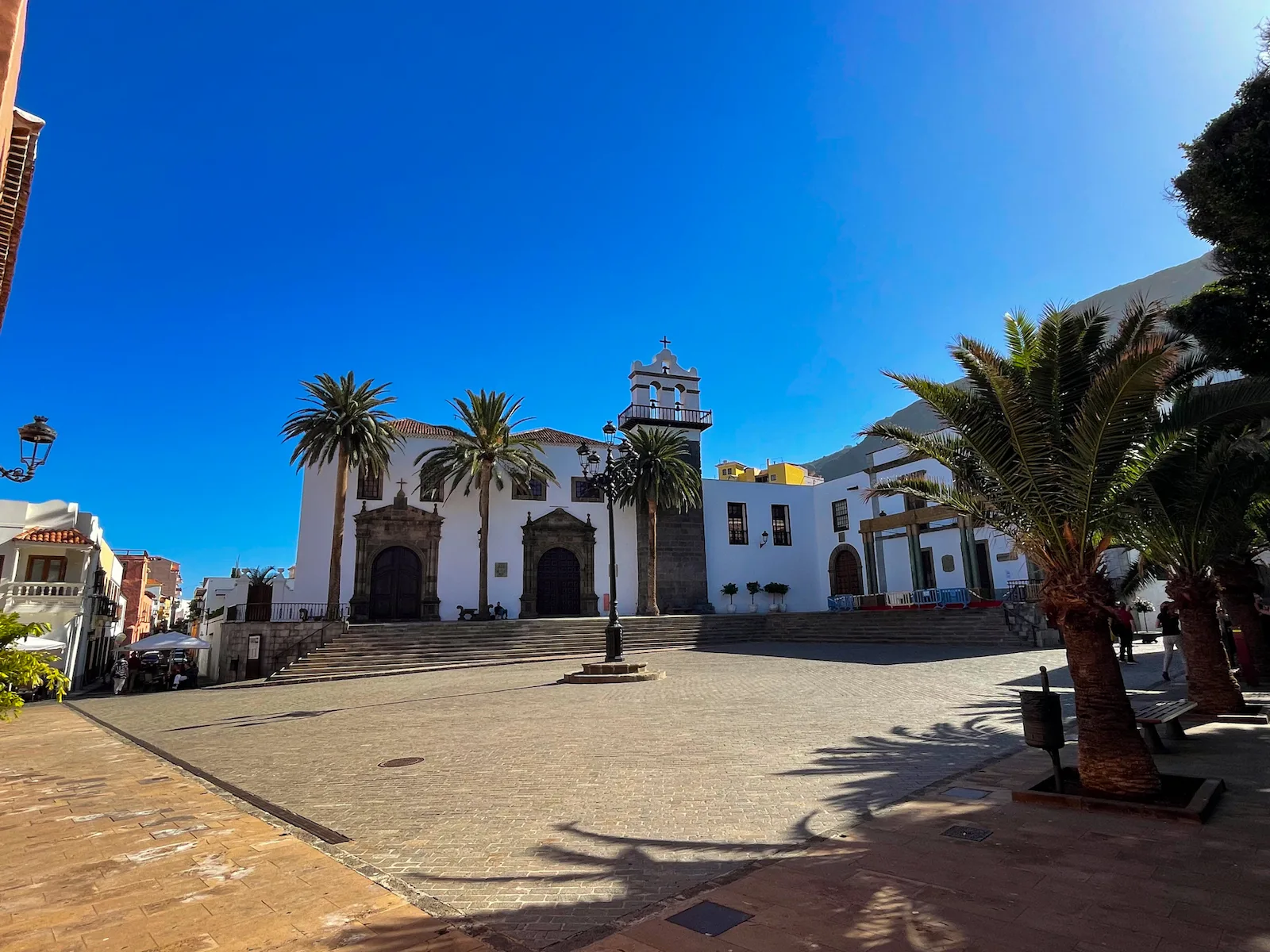 Plaza de la Libertad in Garachico with palm trees and Iglesia de Santa Ana under a blue sky