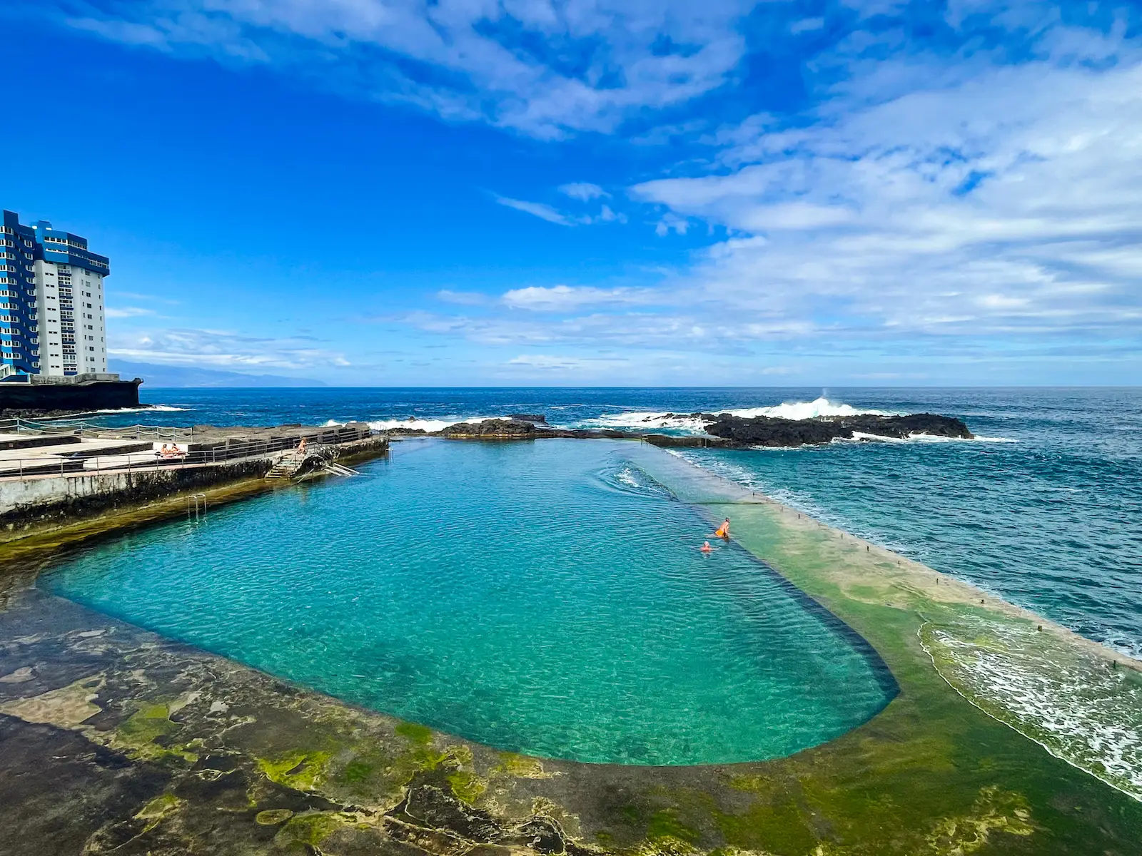 Swimmer in the natural pool of Mesa del Mar with waves nearby