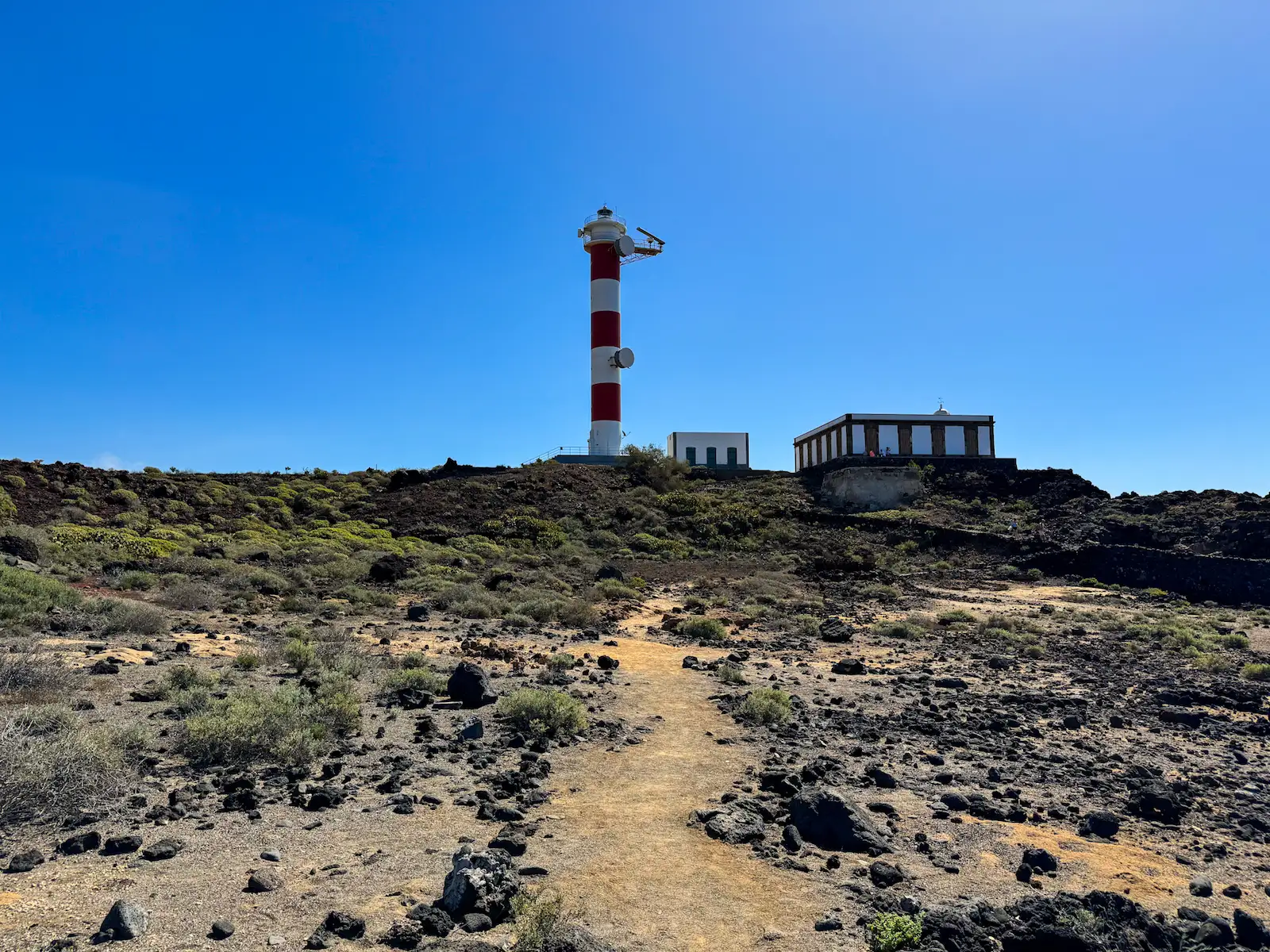 Red and white lighthouse with volcanic rock and ruins