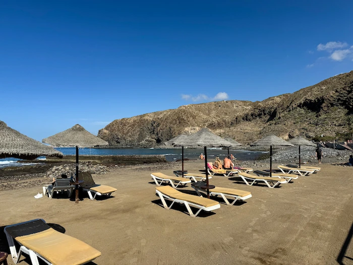 Small beach near Palm-Mar with sunbeds and volcanic cliffs