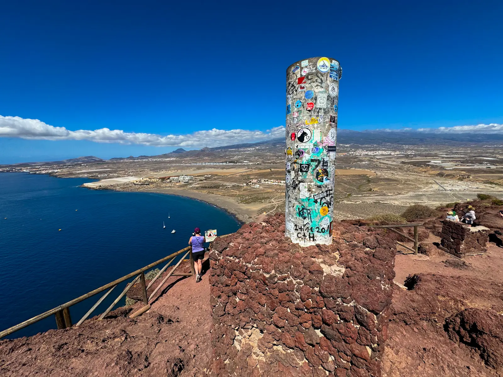 Summit pillar of Montaña Roja with coastal view behind