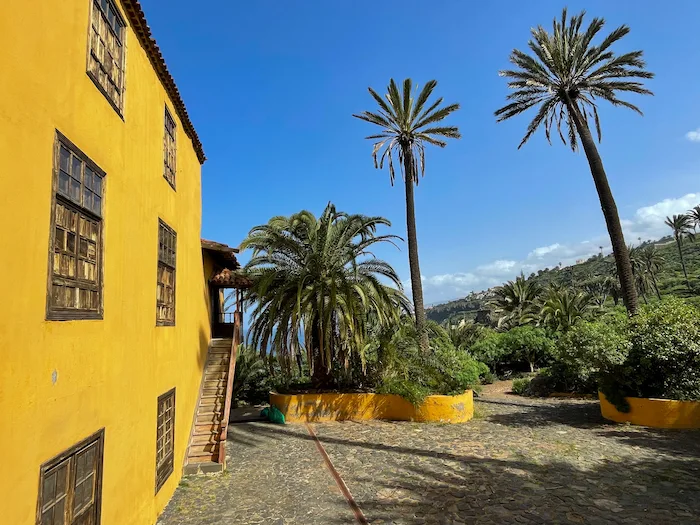 Historic yellow house on the Rambla de Castro hiking trail surrounded by palm trees