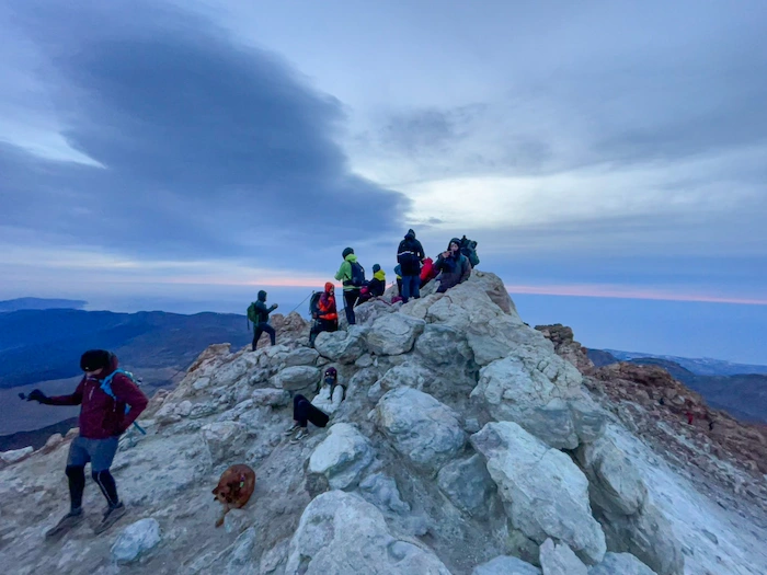 Hikers standing on the summit of Mount Teide with volcanic rocks around
