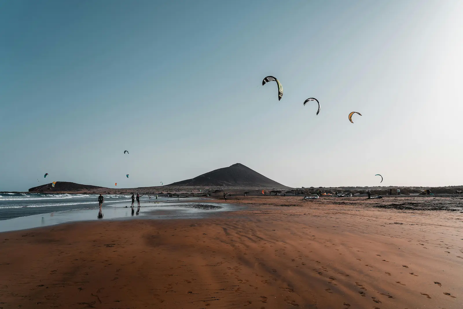 Kitesurfers on the sandy beach of El Médano with Montaña Roja in the background