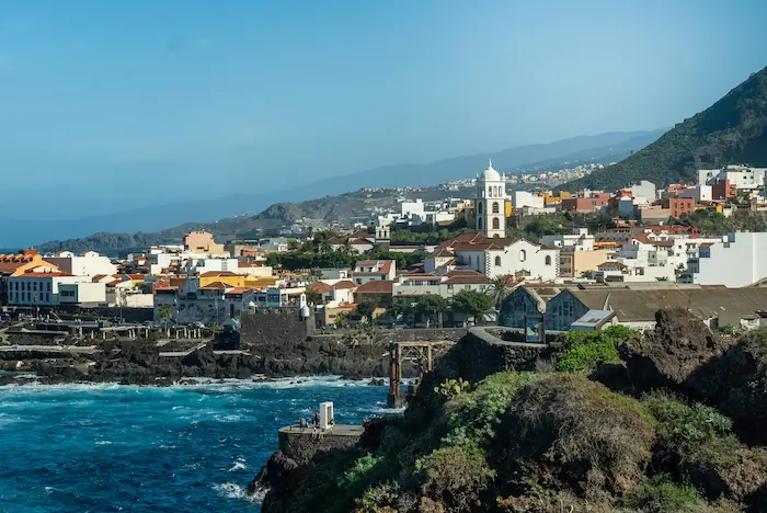 View of Garachico town in Tenerife with its white church tower, coastal cliffs, and turquoise Atlantic Ocean