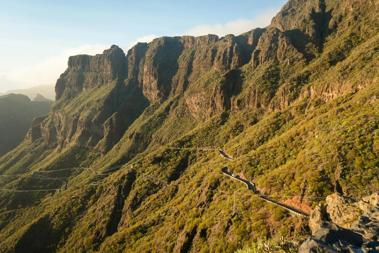 Winding mountain road leading to Masca village through steep cliffs and lush green slopes in Tenerife