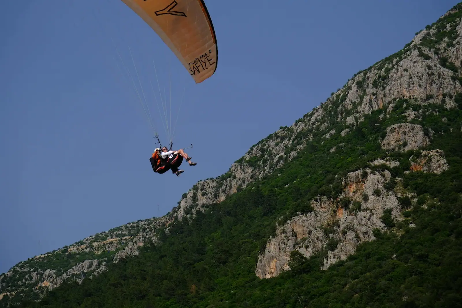 Paraglider flying above green mountains in Tenerife
