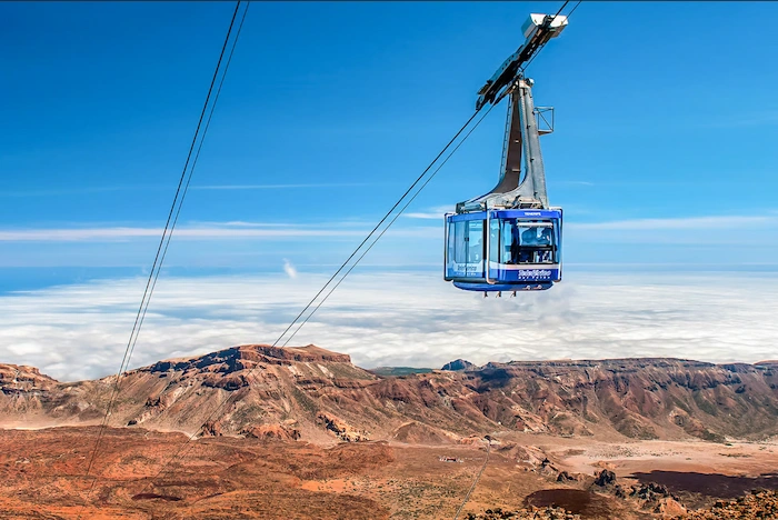 Teide Cable Car ascending above the volcanic landscape and clouds in Tenerife